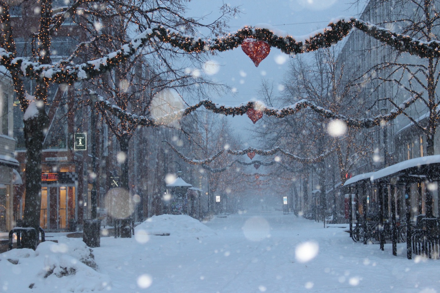 Snøfall i en julepyntet gate i Trondheim sentrum, der julemarkedet holdes.